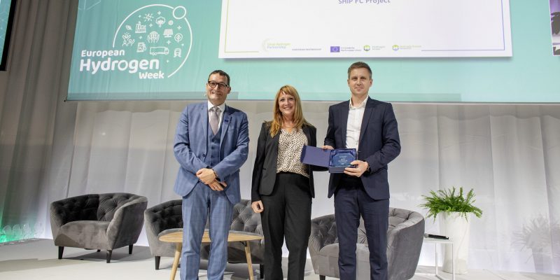 Bart Biebuyck, Executive Director Clean Hydrogen Partnership handed the prize over to Project Coordinator Tore Boge and Communication Lead Kari Stautland, on behalf of the Ship FC project consortium. Photo: Marius Knutsen/Maritime CleanTech